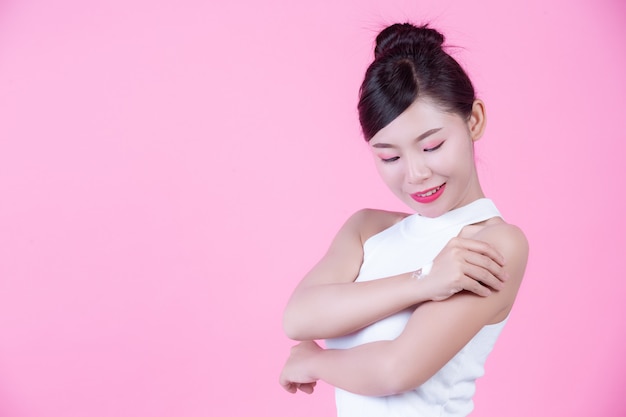Free photo beautiful woman with cream on the skin on a pink background.