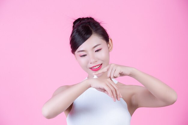 Beautiful woman with cream on the skin on a pink background.