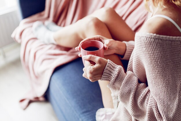 ソファの上のコーヒーのカップを持つ美しい女性