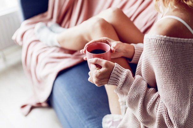 ソファの上のコーヒーのカップを持つ美しい女性