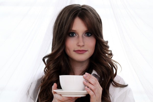 熱いコーヒーのカップを持つ美しい女性