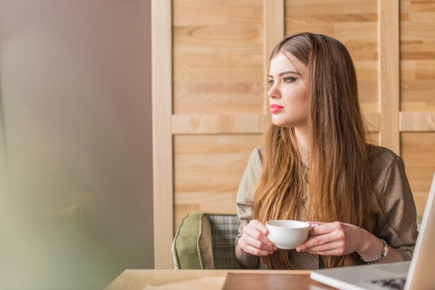 Beautiful woman with cup of tea looking to the side