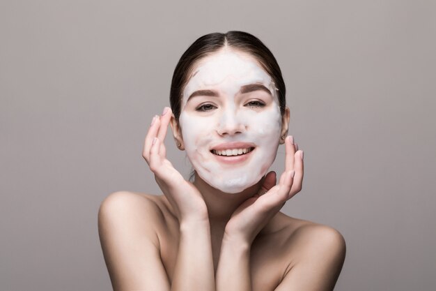 Beautiful woman with facial mask on white wall. Cosmetics, skin care.