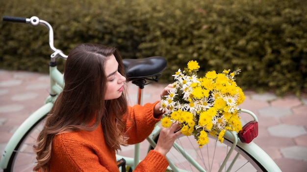 Beautiful woman with flowers and bicycle outdoors