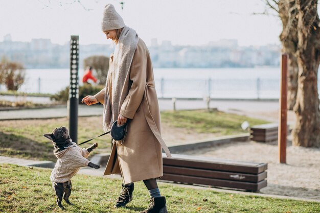 Beautiful woman with french bulldog walking in park