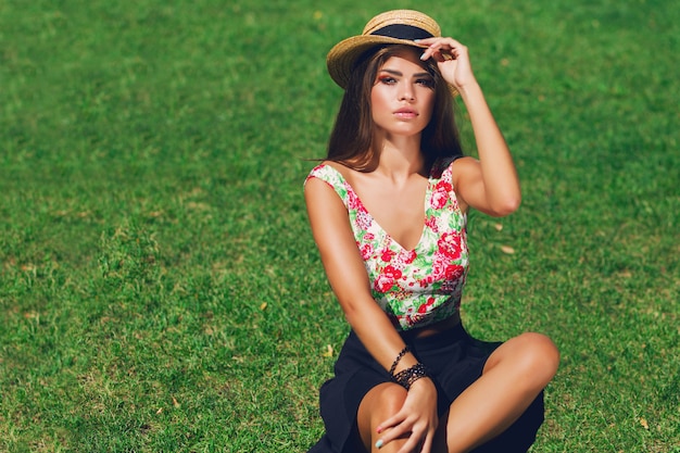 Beautiful woman with hat sitting on grass