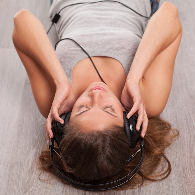 Free photo beautiful woman with headphones lying on the floor