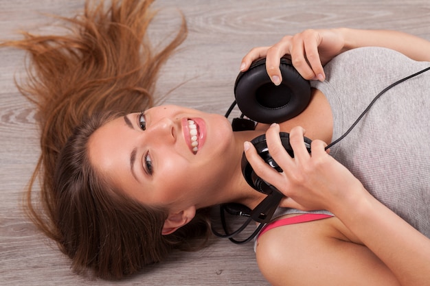 Beautiful woman with headphones lying on the floor