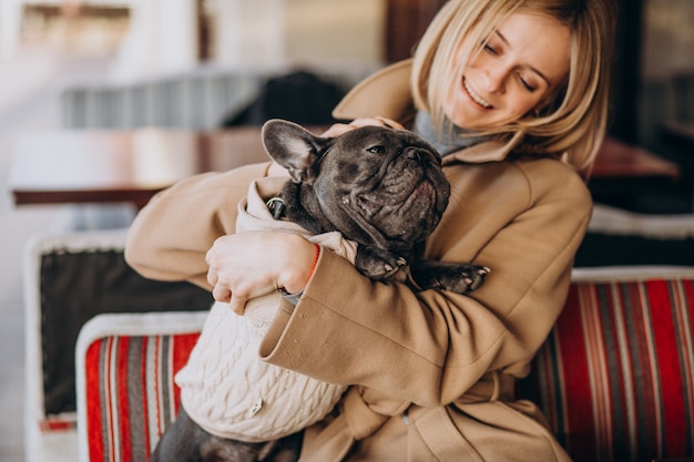 Beautiful woman with her cute french bulldog in warm outfit