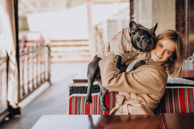 Beautiful woman with her cute french bulldog in warm outfit