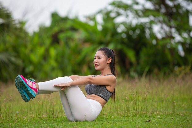 Beautiful woman with long hair exercising on the park lawn.