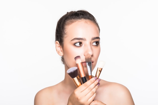 Free photo beautiful woman with makeup brushes near her face isolated on white wall