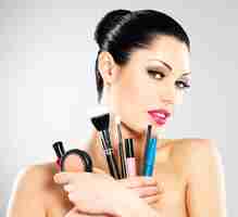 Free photo beautiful woman with makeup brushes near her face. pretty girl poses at studio with cosmetic tools