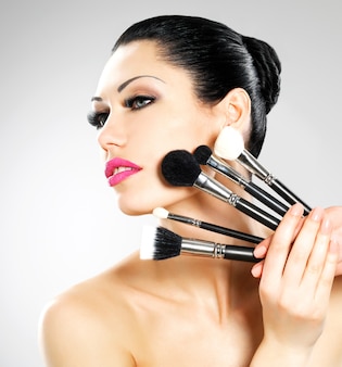 Beautiful woman with makeup brushes near her face. pretty girl poses  with cosmetic tools