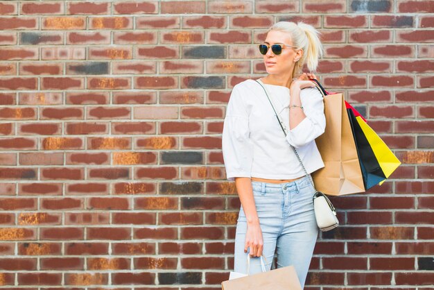 Beautiful woman with packets near wall