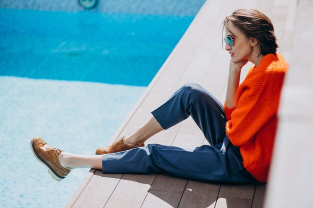 Beautiful woman with phone sitting by the pool