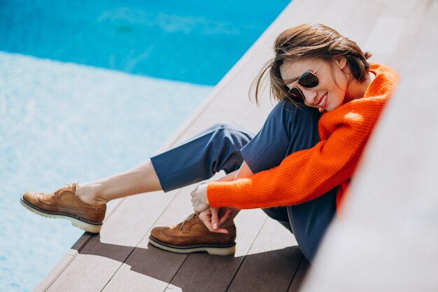 Beautiful woman with phone sitting by the pool