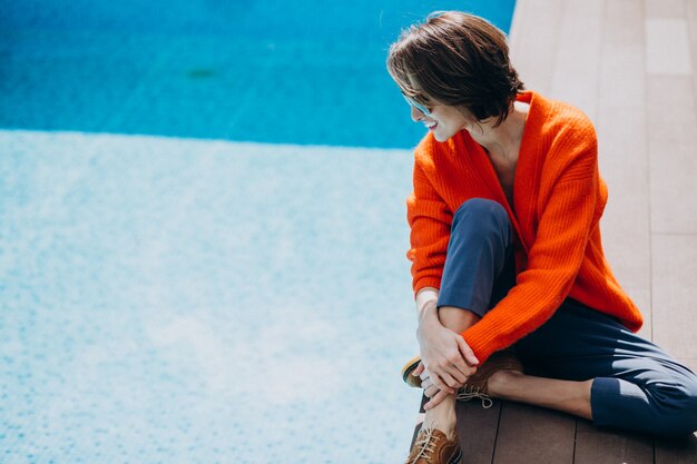 Beautiful woman with phone sitting by the pool