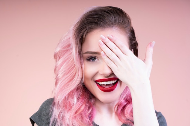 Beautiful woman with red lips covering her left eye with a hand