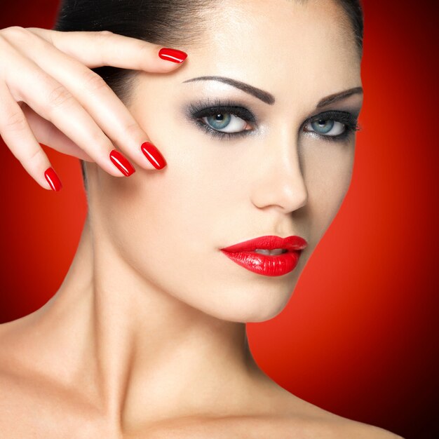 Beautiful woman with red nails and fashion makeup