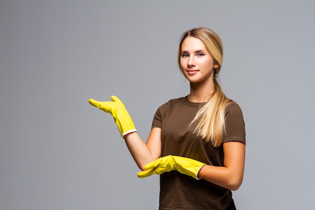 掃除用のゴム手袋をした美しい女性は、白で隔離された側に彼女の手を置きます。