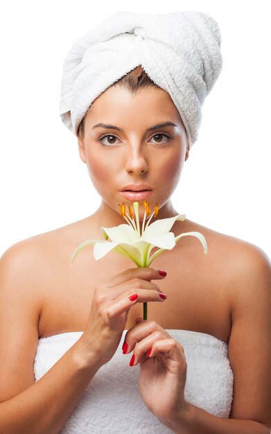 Beautiful woman with towel holding lily