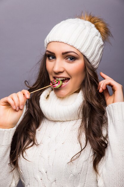 Bella donna con il cappello bianco che tiene lollipop