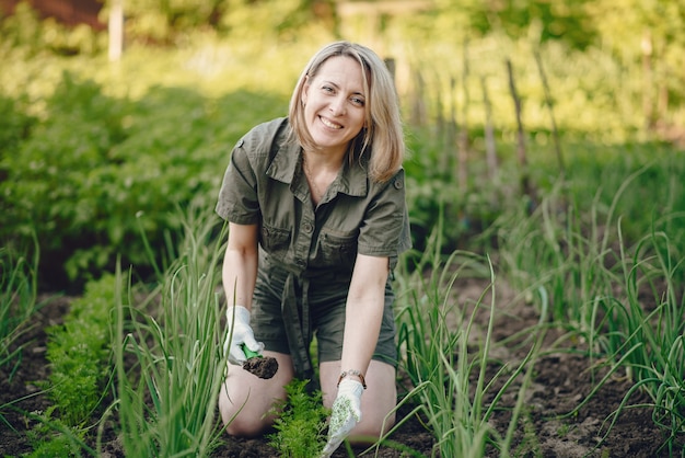 Beautiful woman works in a garden near the house