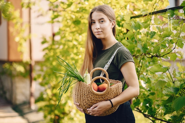 Beautiful woman works in a garden near the house