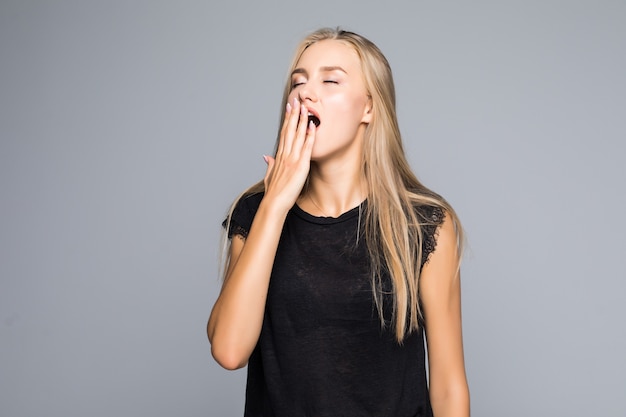 Beautiful woman yawns, bored, isolated on gray background