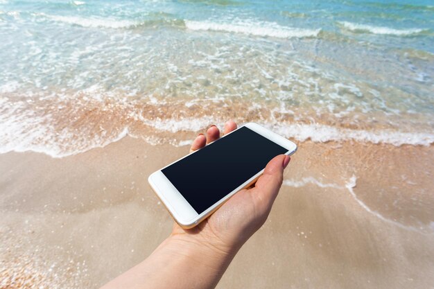 Beautiful womans hand using smart phone at beach