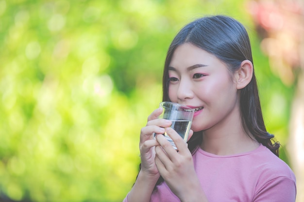 美しい女性はコップ一杯の水からきれいな水を飲む