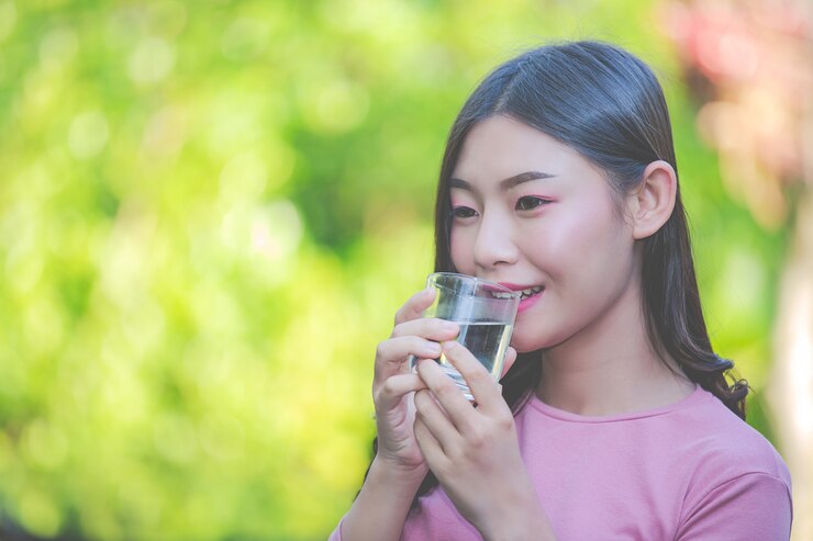 無料Photo 美しい女性はコップ一杯の水からきれいな水を飲む