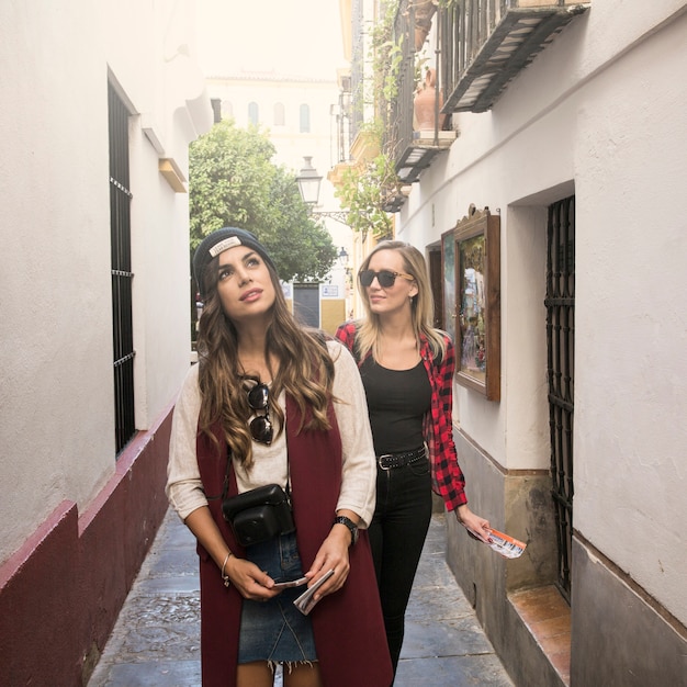 Belle donne che camminano sulla strada stretta