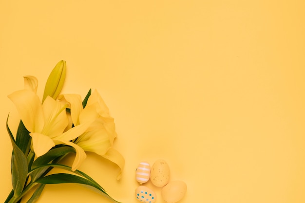 Beautiful yellow lily flower with easter eggs on yellow backdrop