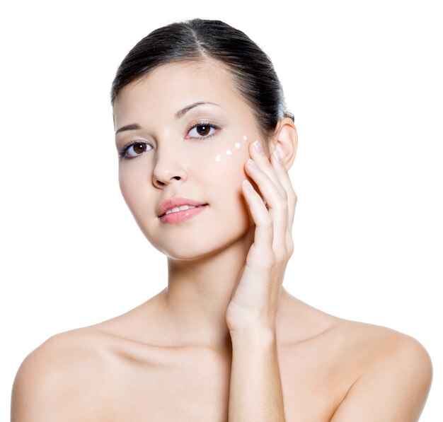 Beautiful young adult  woman applying cosmetic  cream around the eye . 