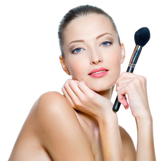 Beautiful young adult woman holds the make-up brushe for applying rouge or powder isolated on white