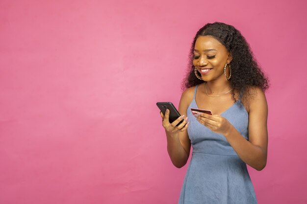 Beautiful young African woman using her mobile phone  and credit card