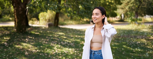 Free photo beautiful young asian girl smiling laughing and walking along park enjoying summer sunny day