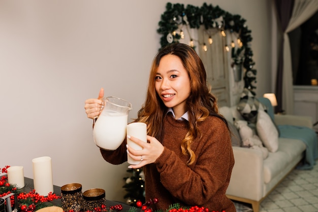 집에서 크리스마스를 축하하고 선물을 여는 동안 즐거운 시간을 보내는 아름다운 아시아 여성 프리미엄 사진