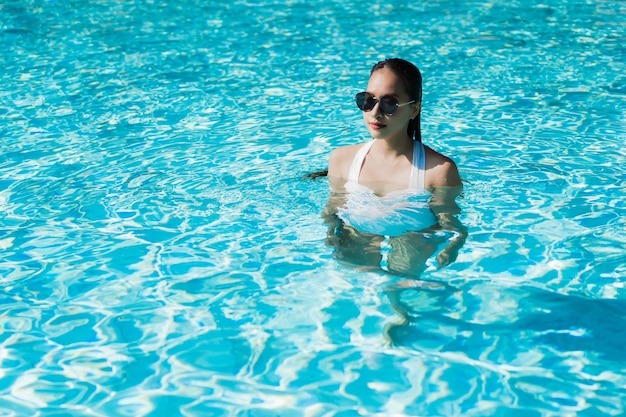 Beautiful young asian woman happy and smile in swimming pool for relax travel and vacation