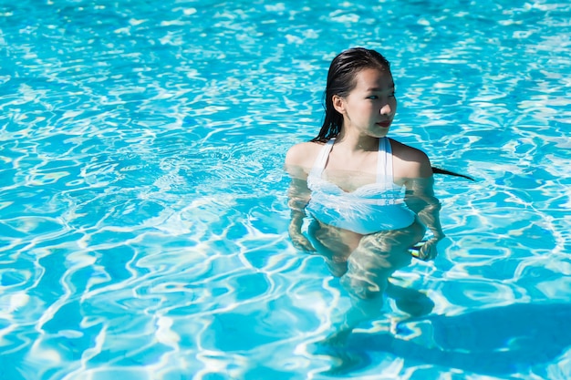 Beautiful young asian woman happy and smile in swimming pool for relax travel and vacation