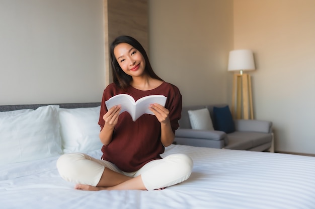 침대에서 아름 다운 젊은 아시아 여자 읽기 책