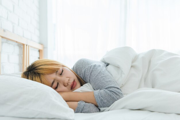 아침에 침대에서 자고 아름다운 젊은 아시아 여성