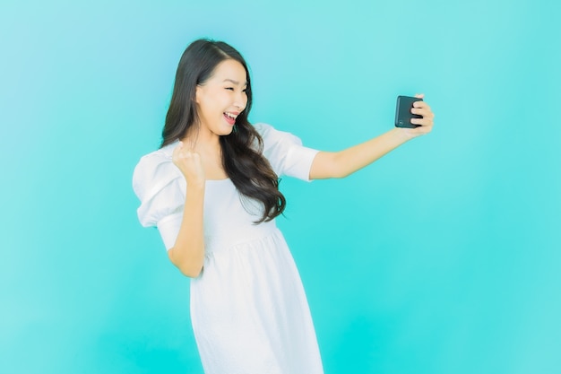 beautiful young asian woman smile with smartphone  on blue