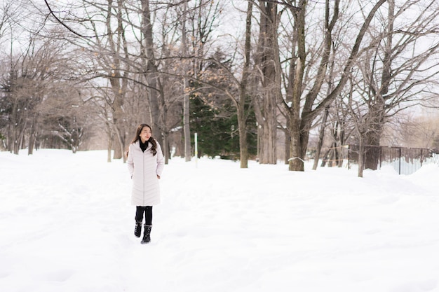 Красивый молодой азиатский усмехаться женщины счастливый для перемещения в сезоне зимы снега