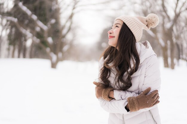 Красивый молодой азиатский усмехаться женщины счастливый для перемещения в сезоне зимы снега