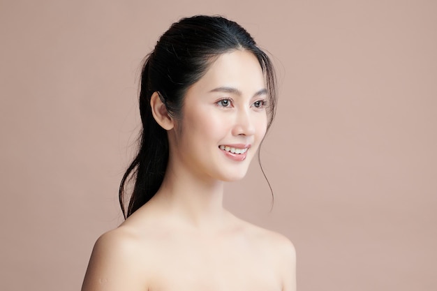 ベージュの背景、フェイスケア、フェイシャルトリートメント、美容、美容とスパ、アジアの女性の肖像画にきれいな新鮮な肌を持つ美しい若いアジアの女性。 Premium写真