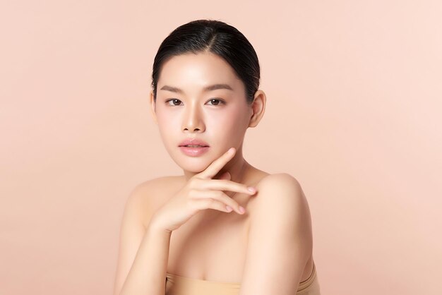 ベージュの背景、フェイスケア、フェイシャルトリートメント、美容、美容とスパ、アジアの女性の肖像画にきれいな新鮮な肌を持つ美しい若いアジアの女性。