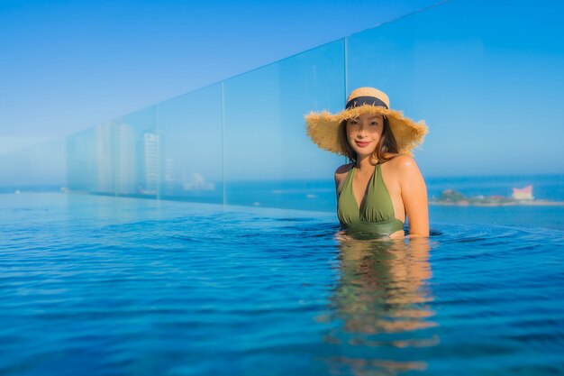 Улыбка красивых молодых азиатских женщин счастливая ослабляет вокруг открытого бассейна в курорте гостиницы для перемещения в каникулах праздника